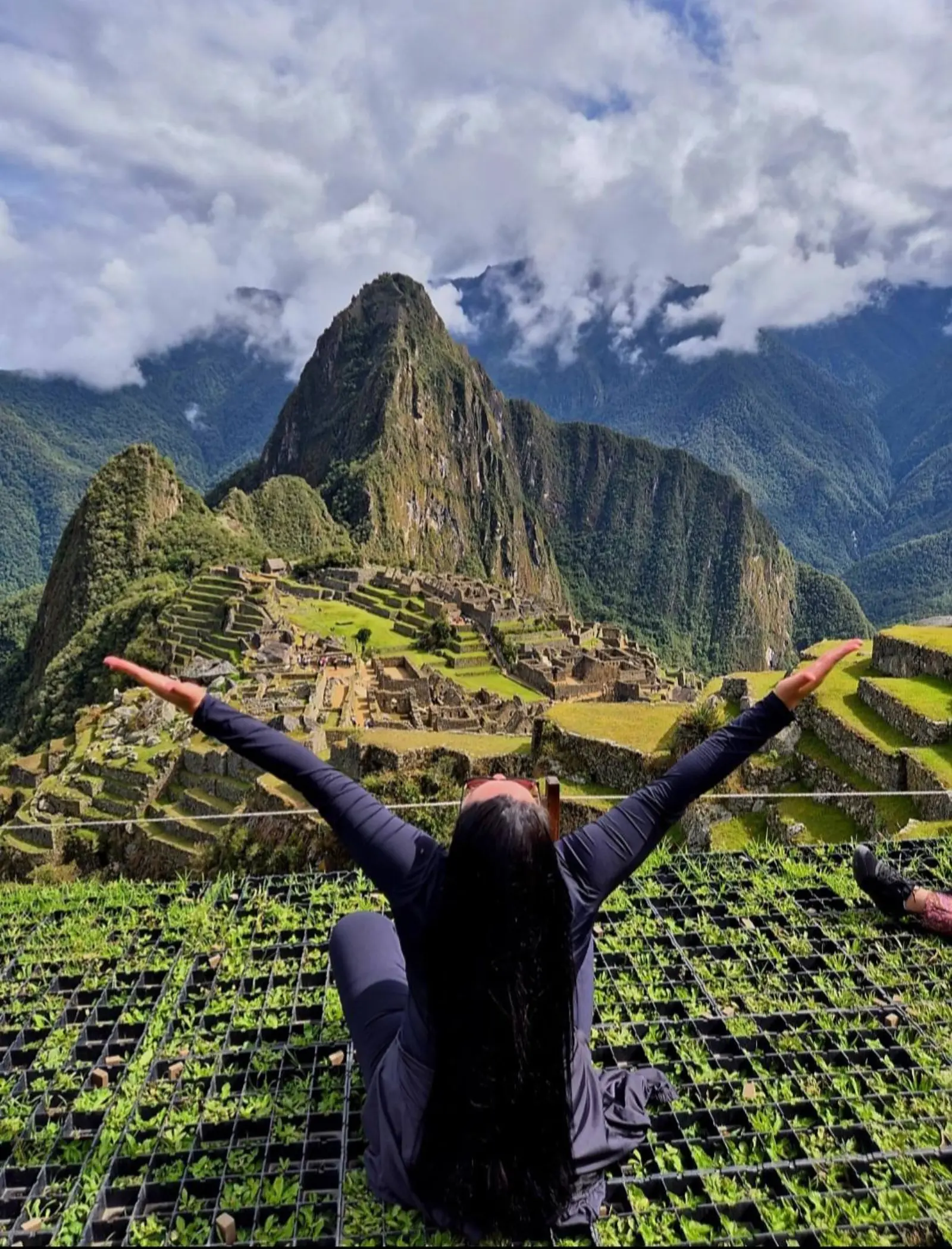 Viajante de braços abertos diante de Machu Picchu